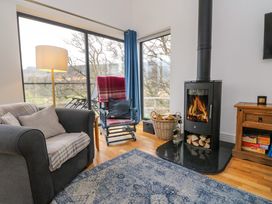 A living room with a wood burning stove armchair rocking chair blue rug and large windows at Dundarach Aberfeldy