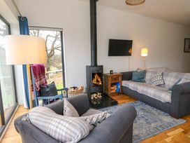 A living room with two sofas a wood burning stove and a side table with a lamp at Dundarach in Aberfeldy