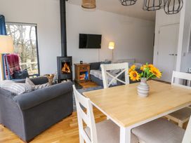 A living room with a sofa a wood stove and a dining table with flowers at Dundarach in Aberfeldy