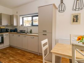 A kitchen with light cabinets a window a wooden dining table with chairs and hanging light fixtures at Dundarach in Aberfeldy