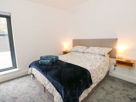 A bedroom with a bed with patterned bedding two bedside tables with lamps and a window at Dundarach in Aberfeldy