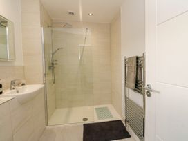 A bathroom with a walk-in shower a sink with a mirror and a towel rack at Dundarach in Aberfeldy