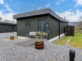 A modern black wooden building with a bench and a potted plant outside at Dundarach in Aberfeldy
