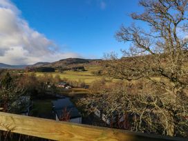 A landscape view of fields hills and trees with a wooden fence in the foreground at Dundarach Aberfeldy