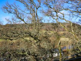 Trees with bare branches overlooking a house with solar panels and a landscape with hills and a river at Dundarach in Aberfeldy
