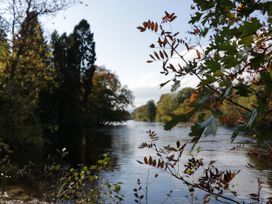 A river surrounded by trees with branches and leaves in the foreground at Dundarach in Aberfeldy