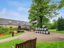A building with ivy on the walls and a stack of barrels spelling home of dewars in front of a tree at Dundarach in Aberfeldy