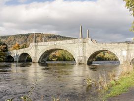 A stone arch bridge over a river with hills and trees in the background at Dundarach in Aberfeldy