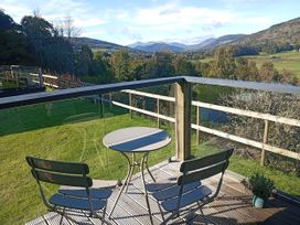 An outdoor seating area with a table and chairs overlooking the mountains at Dundarach in Aberfeldy