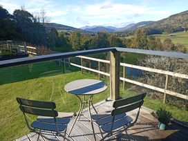 A balcony with a table and chairs overlooking mountains at Dundarach in Aberfeldy