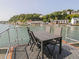 An outdoor area with a table and chairs overlooking water and boats at Seafarer's Haven in Porthmadog