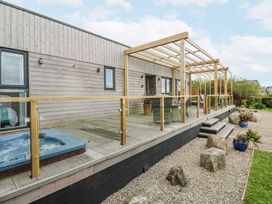An outdoor area with a hot tub and wooden deck at Petroc in Portreath