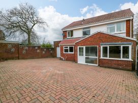 A brick driveway with a red brick house and a high brick wall with ventilation blocks at 14 Birchwood Road in Woolaston