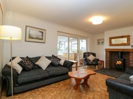 A living room with grey sofas and a wooden coffee table with a fireplace in the corner at 14 Birchwood Road in Woolaston