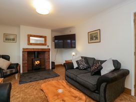 A living room with a fireplace a wall-mounted television a gray sofa and a wooden coffee table at 14 Birchwood Road in Woolaston
