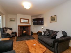 A living room with a fireplace armchair sofa wooden coffee table and mounted television at 14 Birchwood Road in Woolaston