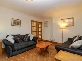 A living room with two sofas a wooden coffee table a floor lamp and framed pictures on the walls at 14 Birchwood Road in Woolaston