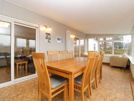 A dining room with a wooden table and chairs and a sitting area by the windows at 14 Birchwood Road in Woolaston