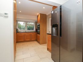 A kitchen with wooden cabinets a stainless steel refrigerator and a window above the sink at 14 Birchwood Road in Woolaston
