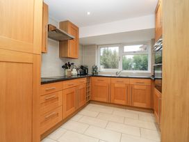 A kitchen with wooden cabinets black countertops and a window at 14 Birchwood Road in Woolaston