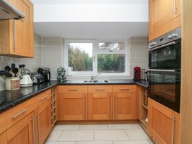 A kitchen with wooden cabinets black countertops a double sink a window and stainless steel appliances at 14 Birchwood Road in Woolaston