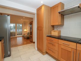 A kitchen with wooden cabinets and black countertop next to a room with wooden floor and glass doors at 14 Birchwood Road in Woolaston
