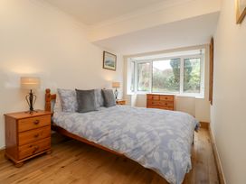 A bedroom with a bed and wooden furniture including bedside tables and a chest of drawers at 14 Birchwood Road in Woolaston