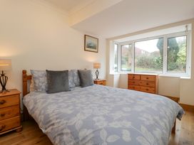 A bedroom with a double bed between two nightstands with lamps and a dresser under a bay window at 14 Birchwood Road in Woolaston