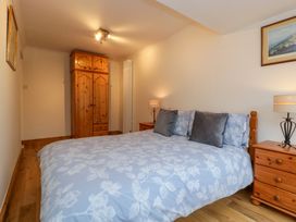 A bedroom with a large bed wooden bedside tables lamps a wooden wardrobe and framed pictures on the wall at 14 Birchwood Road in Woolaston
