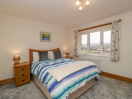 A bedroom with a double bed and wooden bedside tables with lamps next to a window at 14 Birchwood Road in Woolaston