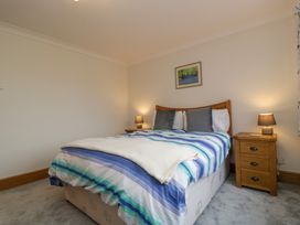A bedroom with a bed with striped bedding and two bedside tables with lamps at 14 Birchwood Road in Woolaston