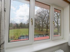 A view of a grassy field and trees through a white framed window at 14 Birchwood Road in Woolaston