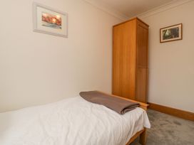 A bedroom with a single bed and a wooden wardrobe and two framed pictures on the walls at 14 Birchwood Road in Woolaston