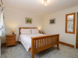 A bedroom with a wooden bed and matching bedside tables lamps and framed pictures on the walls at 14 Birchwood Road in Woolaston