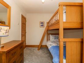 A bedroom with a wooden bunk bed a dresser with a lamp and a wooden door at 14 Birchwood Road in Woolaston
