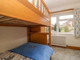 A bedroom with a wooden bunk bed next to a window with floral curtains at 14 Birchwood Road in Woolaston