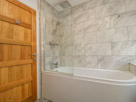 A bathroom with a bathtub shower combination glass partition and a wooden door at 14 Birchwood Road in Woolaston