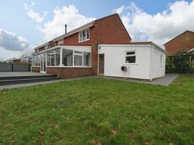 A backyard with grass and a house with a glass conservatory and white extension at 14 Birchwood Road in Woolaston
