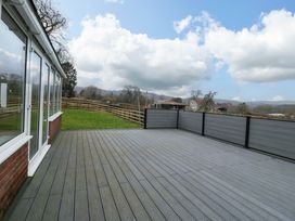 A large outdoor deck with railing next to a house and a grassy yard at 14 Birchwood Road in Woolaston
