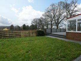 A backyard with grass lawn wooden fence and a house with a small porch at 14 Birchwood Road in Woolaston