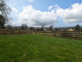 A grassy fenced field with houses and trees in the distance at 14 Birchwood Road in Woolaston