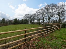 A grassy field enclosed by a wooden fence with leafless trees and a partly cloudy sky at 14 Birchwood Road in Woolaston