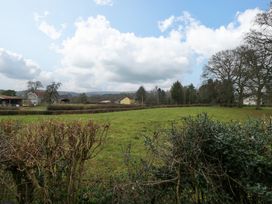 A field with trimmed bushes and trees with houses and farmland in the background at 14 Birchwood Road in Woolaston