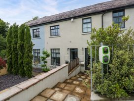 An outdoor area with a house, pathway, plants, and a charging station at The Old Creamery in Ffairfach