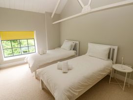 A bedroom with two single beds and a window at The Old Creamery in Ffairfach