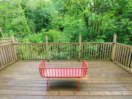 A deck with a red bench surrounded by trees at The Old Creamery in Ffairfach