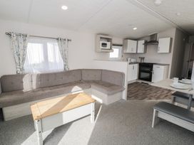 A living room with a sofa and kitchenette at Gold Caravan (316) Talybont
