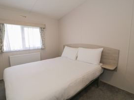 A bedroom with a bed and window at Gold Caravan (316) Talybont