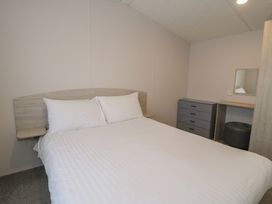A bedroom with a bed and a desk with a mirror at Gold Caravan (316) Talybont