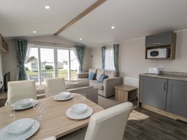 A living room with a dining area and a sofa at Gold Caravan (203) Talybont